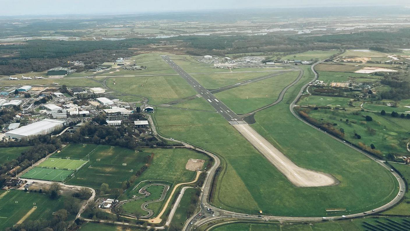 Aerial shot of Bournemouth Airport runway, a long tarmac strip surrounded by grass.