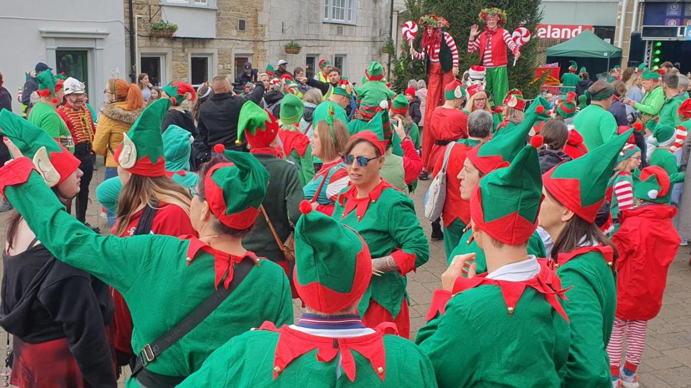 Lots of people dressed as elves in green and red costumes with pointy hats