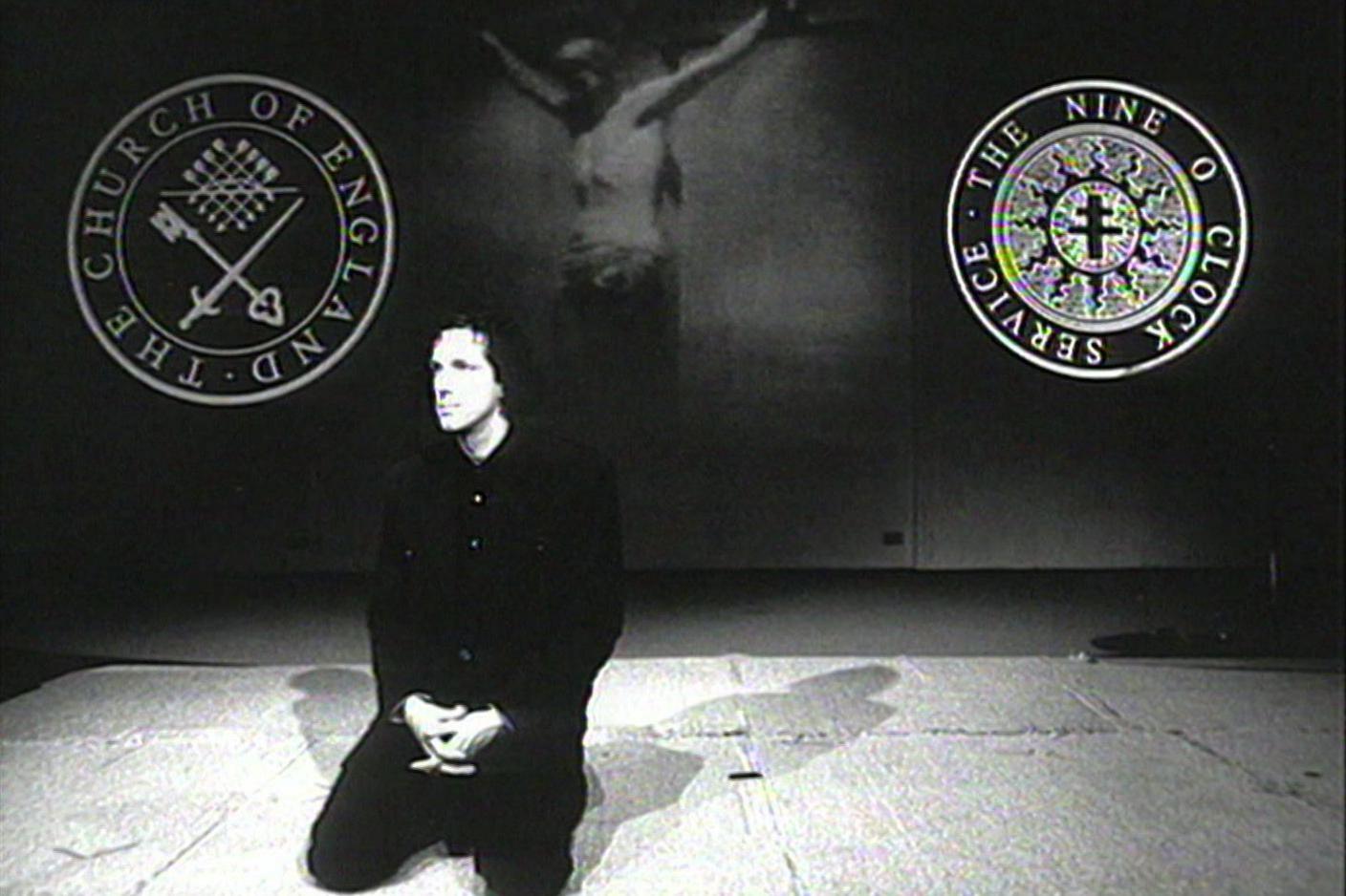 A black-and-white image shows Chris Brain wearing dark clothing as he kneels on the floor, his hands in his lap. Behind him is an image of Jesus on the cross as well as the Church of England and Nine O'Clock Service logos.