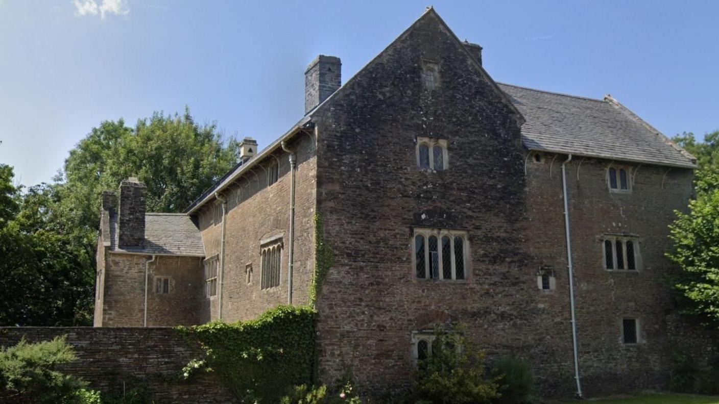 A large tudor style building surrounded by trees.