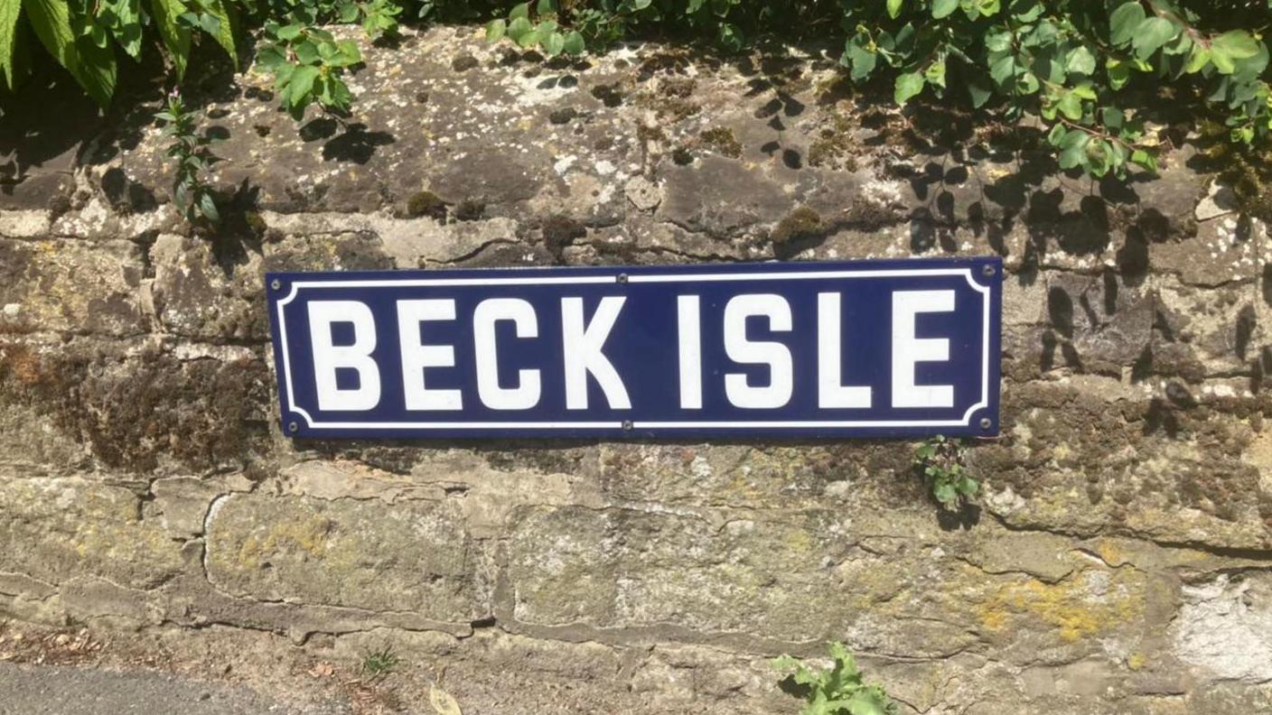 One of the new blue and white street signs, fixed to a wall 