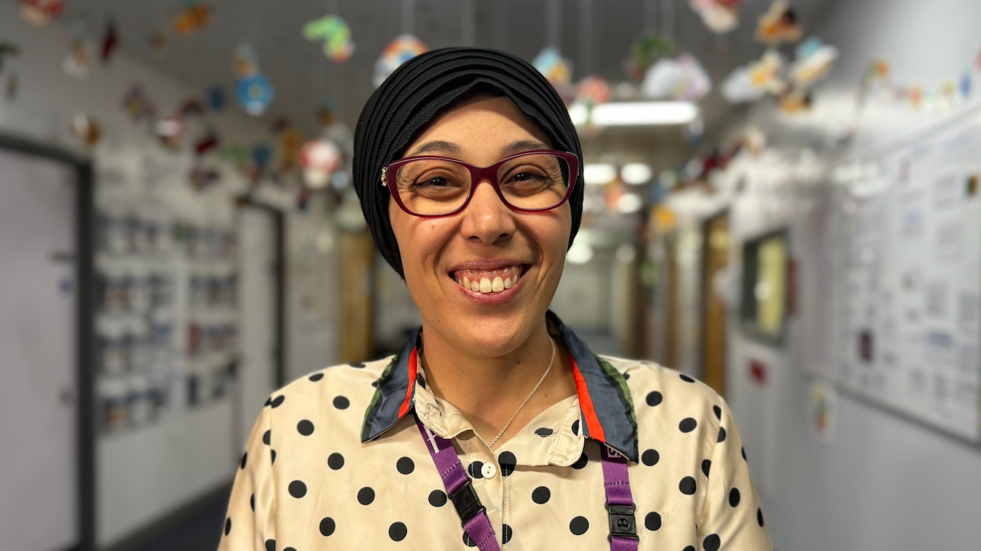 A doctor wearing a headscarf, glasses and a spotted T-shirt.