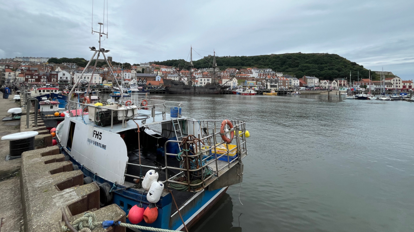 Scarborough harbour with a fishing boat in the foreground and the town in the background