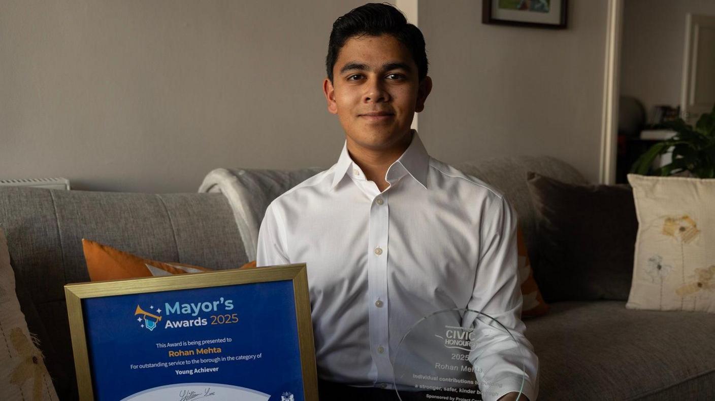 Rohan in his Kensington home holding two awards