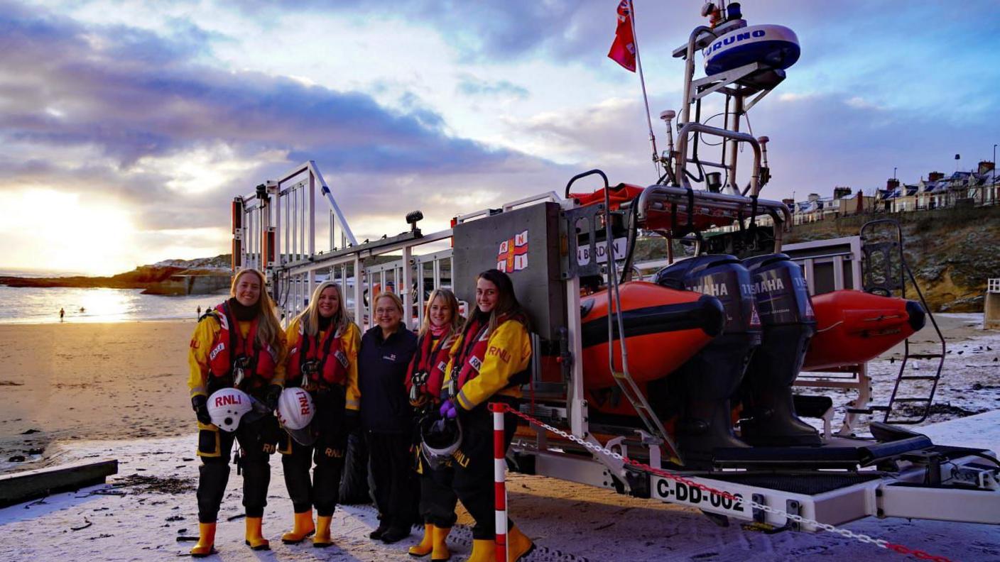 Anna Heslop standing alongside a lifeboat with four other female RNLI team members