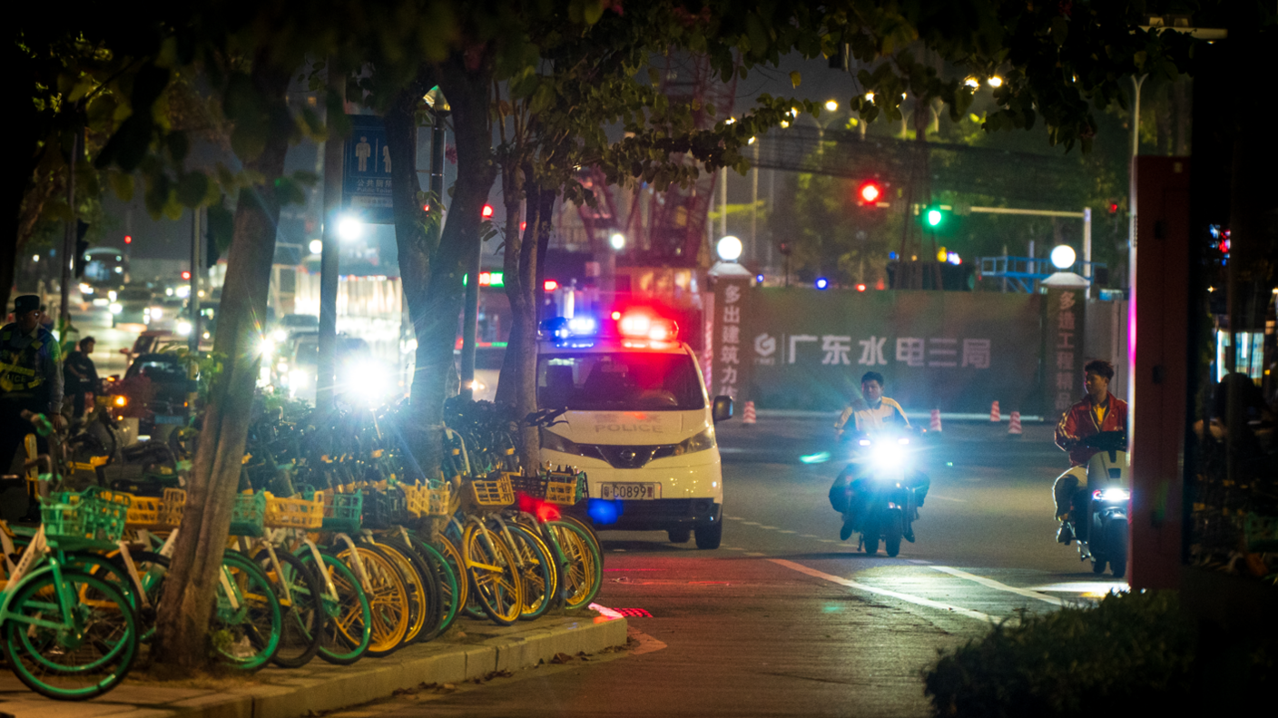 A police van and motorcylists waiting on the street outside the stadium venue on 12/11/24. It is night time.