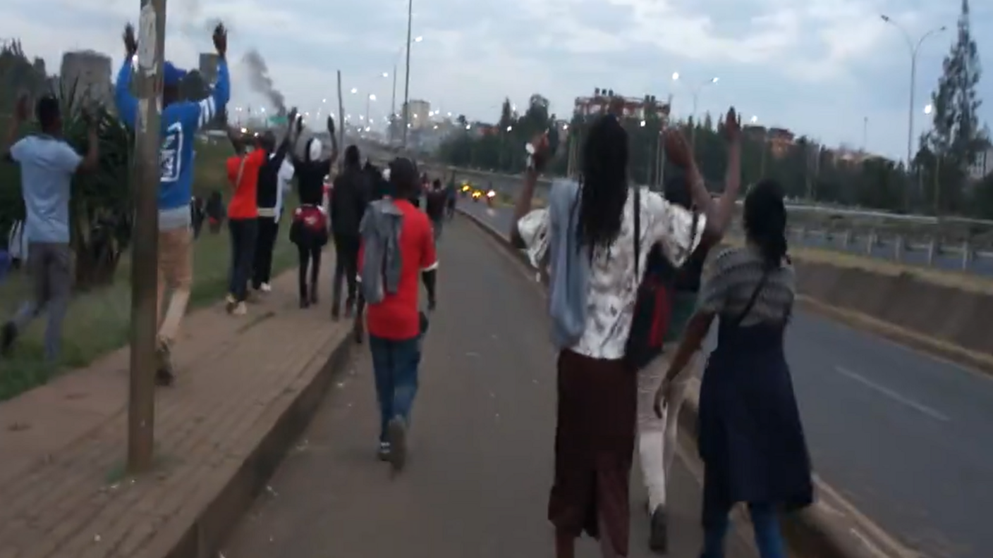 People walking along a road with their hands up