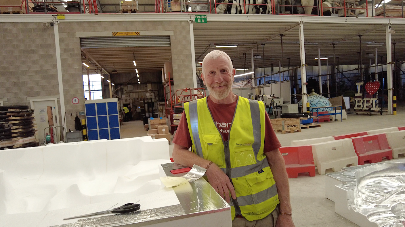 Production laminator Gary Arnold in a hi vis vest working on a fibreglass mould 