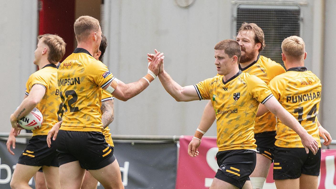 Two Cornwall players put their hands together to celebrate a try