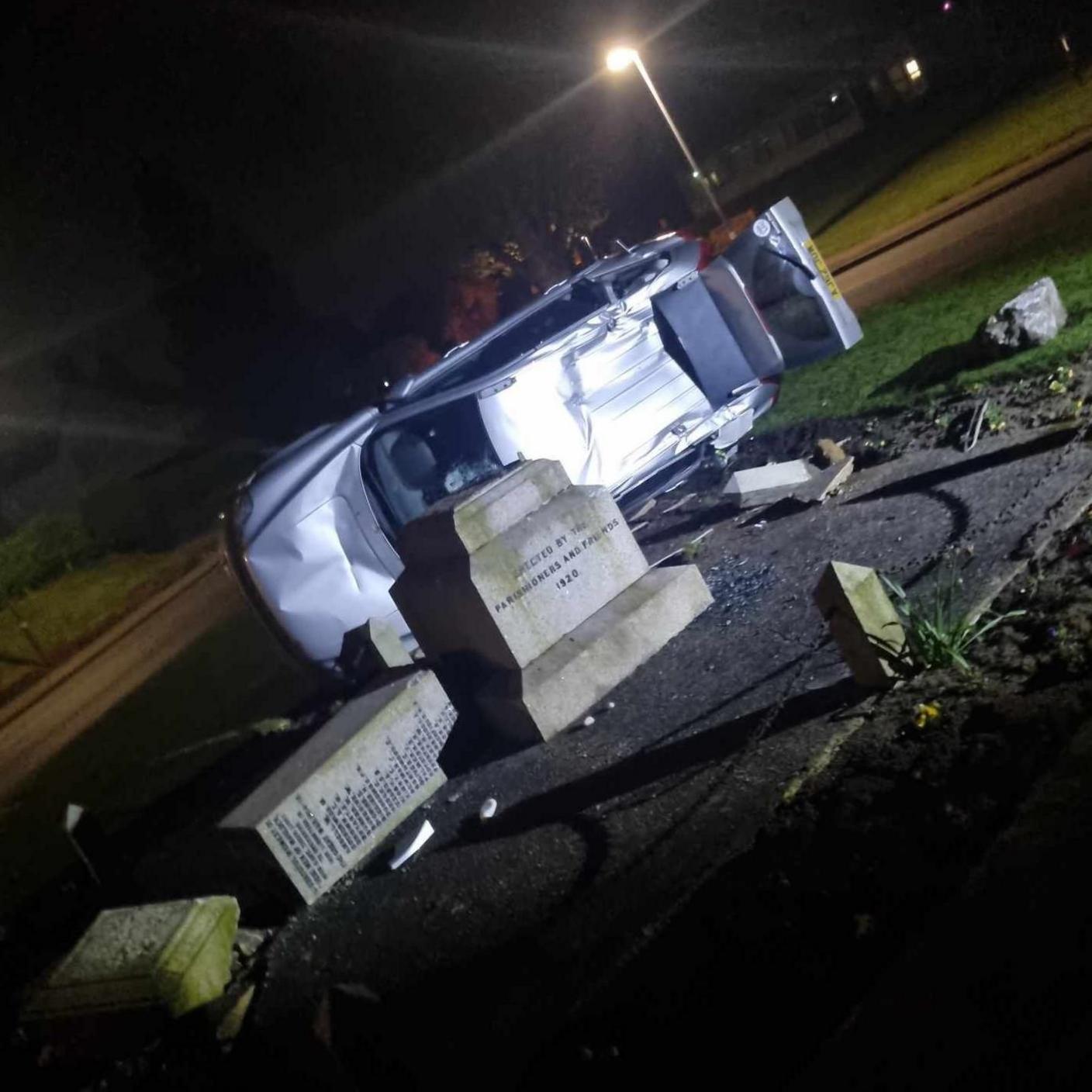 The toppled memorial with a car laying on its side