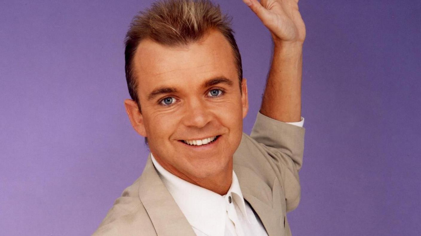 Wayne Dobson in his 1990s heyday wearing suit jacket and spiky hair