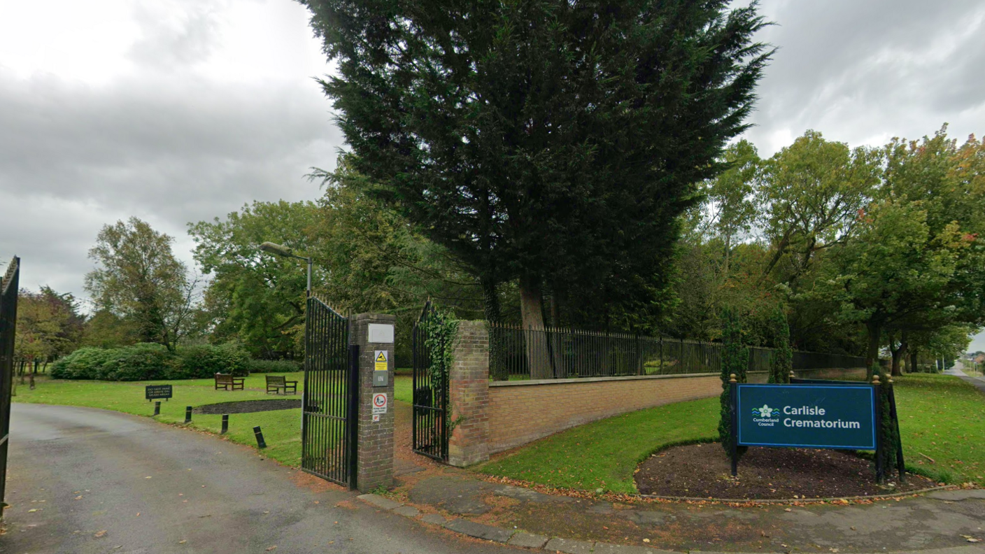The gates to Carlisle Crematorium. There is a blue sign