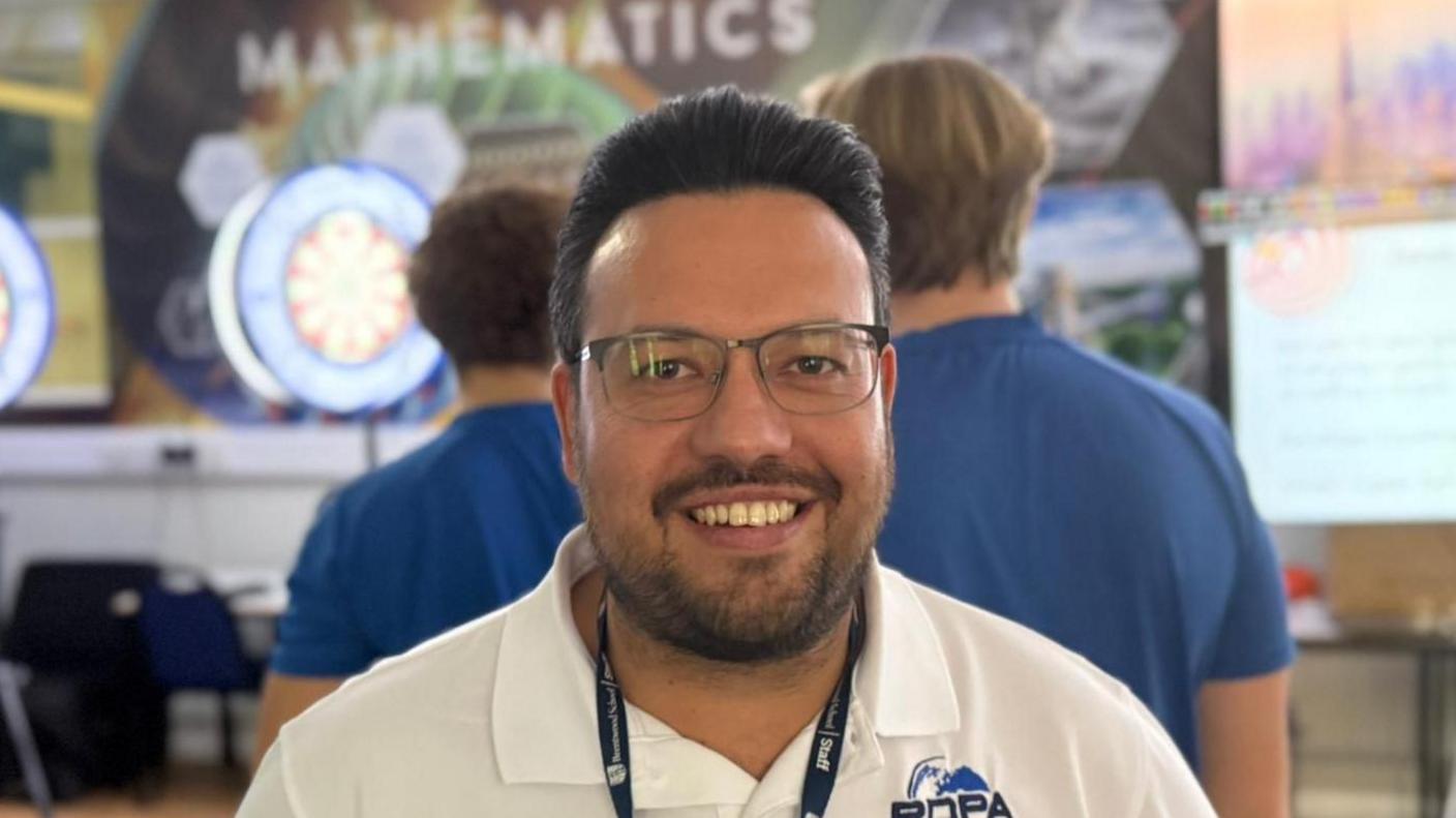 A man with glasses and a landyard around his neck