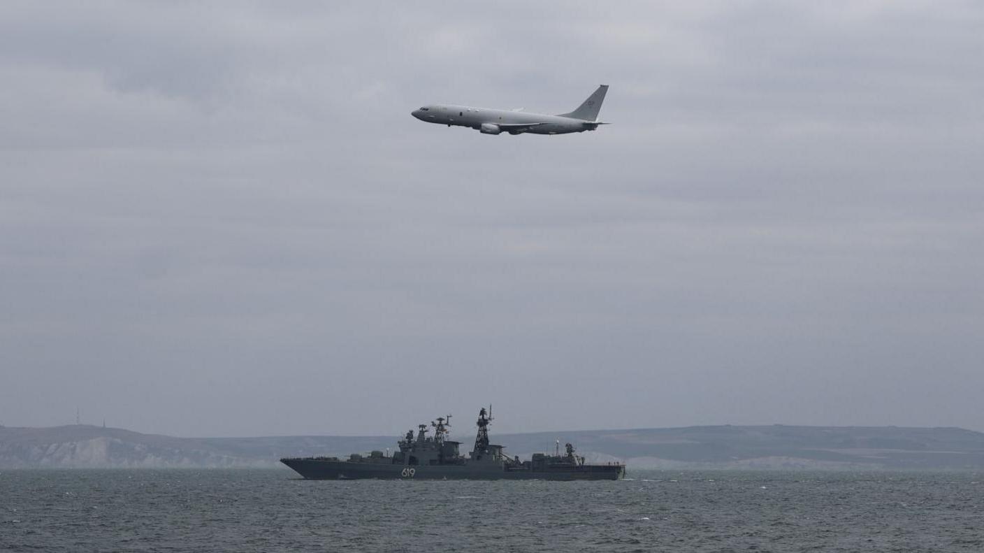 Image shows an RAF maritime patrol aircraft in the sky over a Russian warship