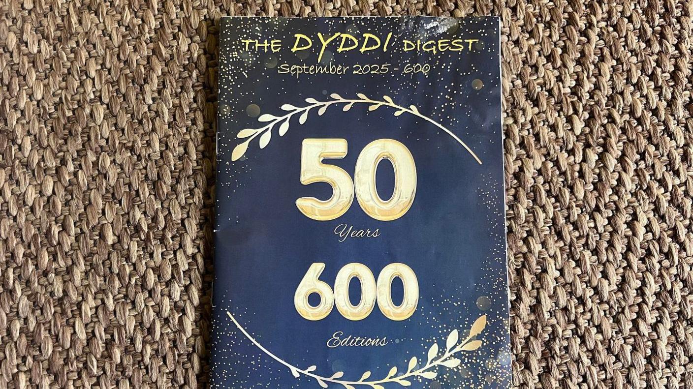 A blue edition of the Dyddi which has gold writing saying 50th year and 600th edition.