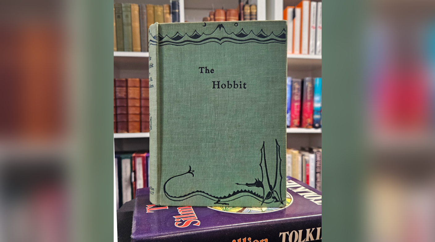 A copy of The Hobbit book. It is green with black text and an illustration at the bottom of the cover.