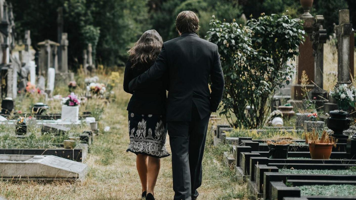 Sad couple walking through a cemetery