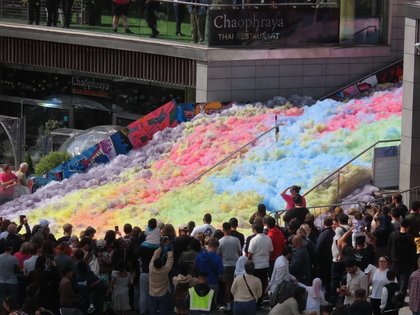 An expanse of multi-coloured foam outside Chaophraya Thai restaurant at the Bullring shopping centre. A large crowd of people is standing around it, many taking pictures on smartphones.