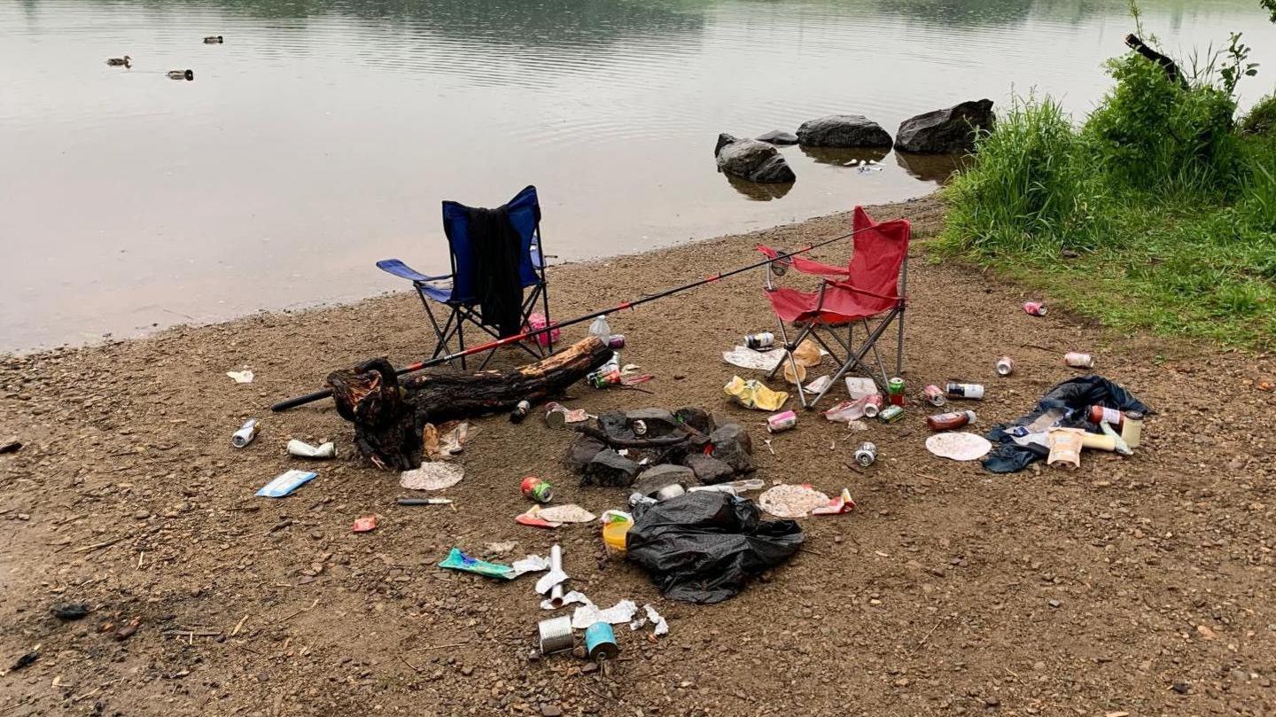 Piles of rubbish and discarded camping equipment on the banks of a loch