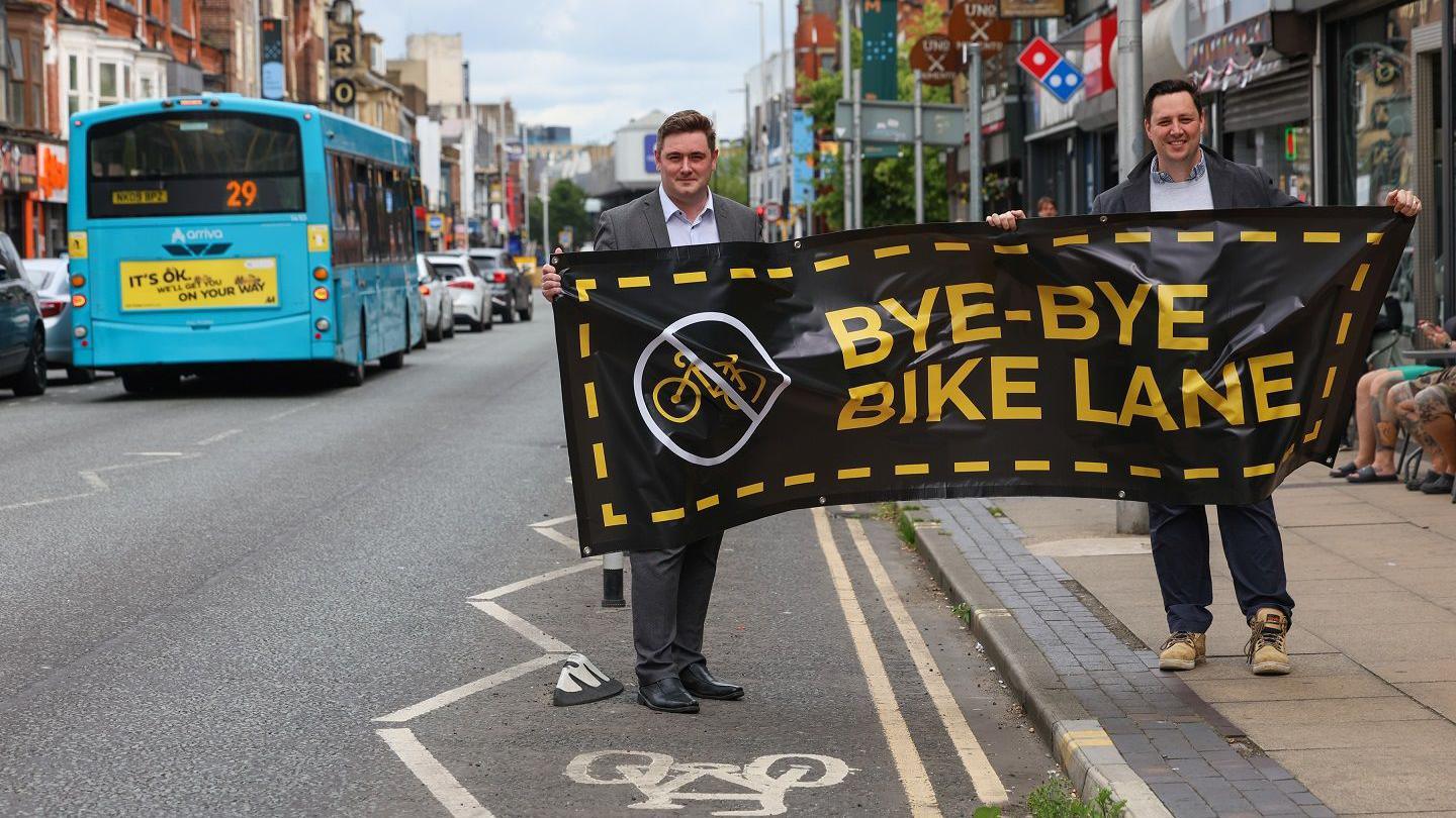 Middlesbrough Mayor Chris Cooke (left) and Tees Valley Mayor Lord Houchen holding a banner reading "Bye-bye bike lane".