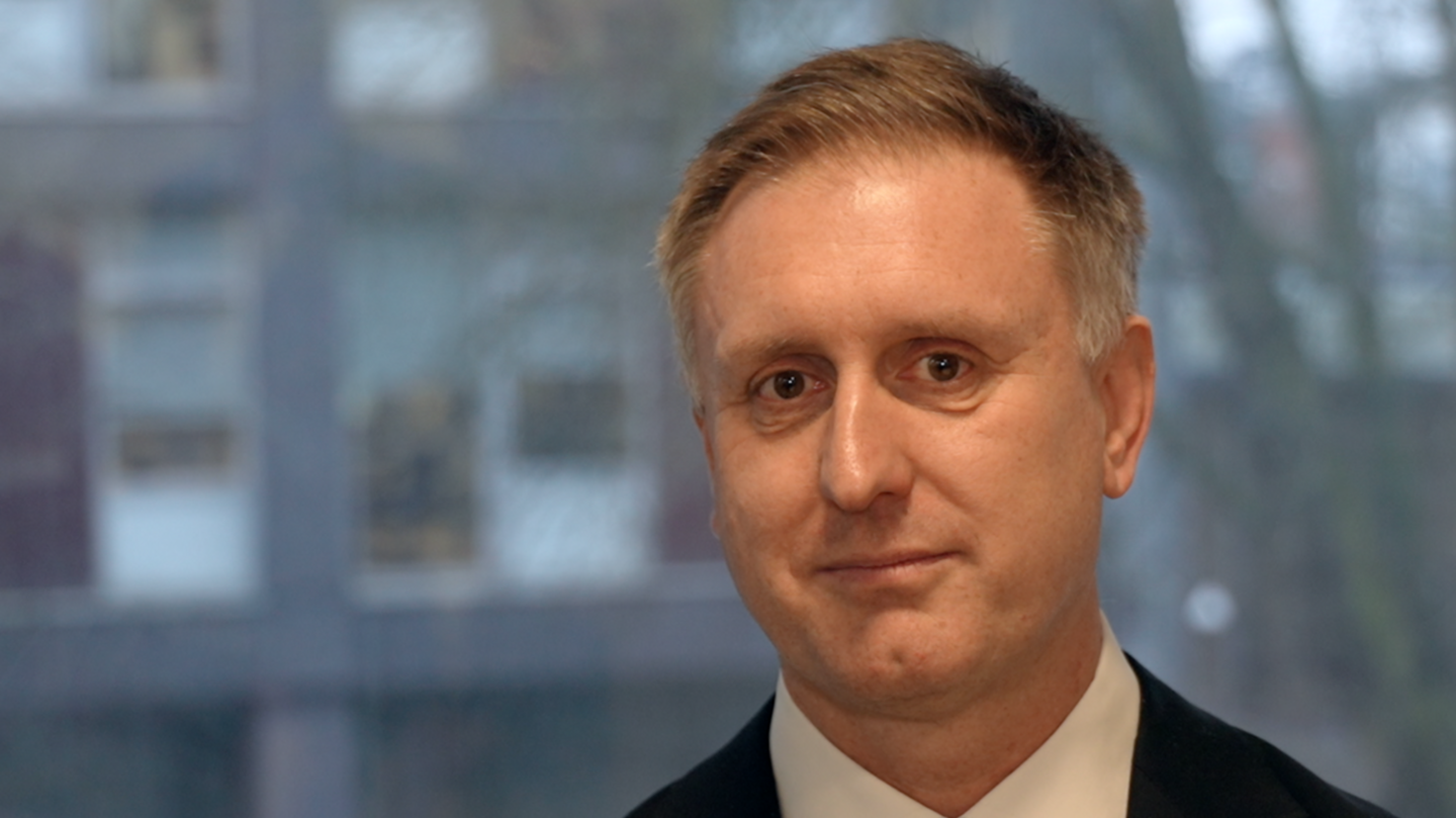 Ed Garrett with short light brown hair wearing a shirt and tie. He is looking into the camera.