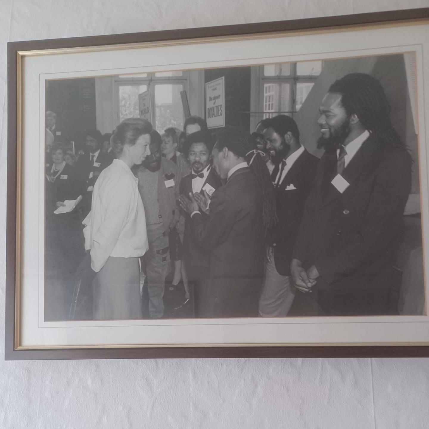 Photo of a black and white photo inside a frame of Princess Anne meeting various members of Brafa who are wearing suits