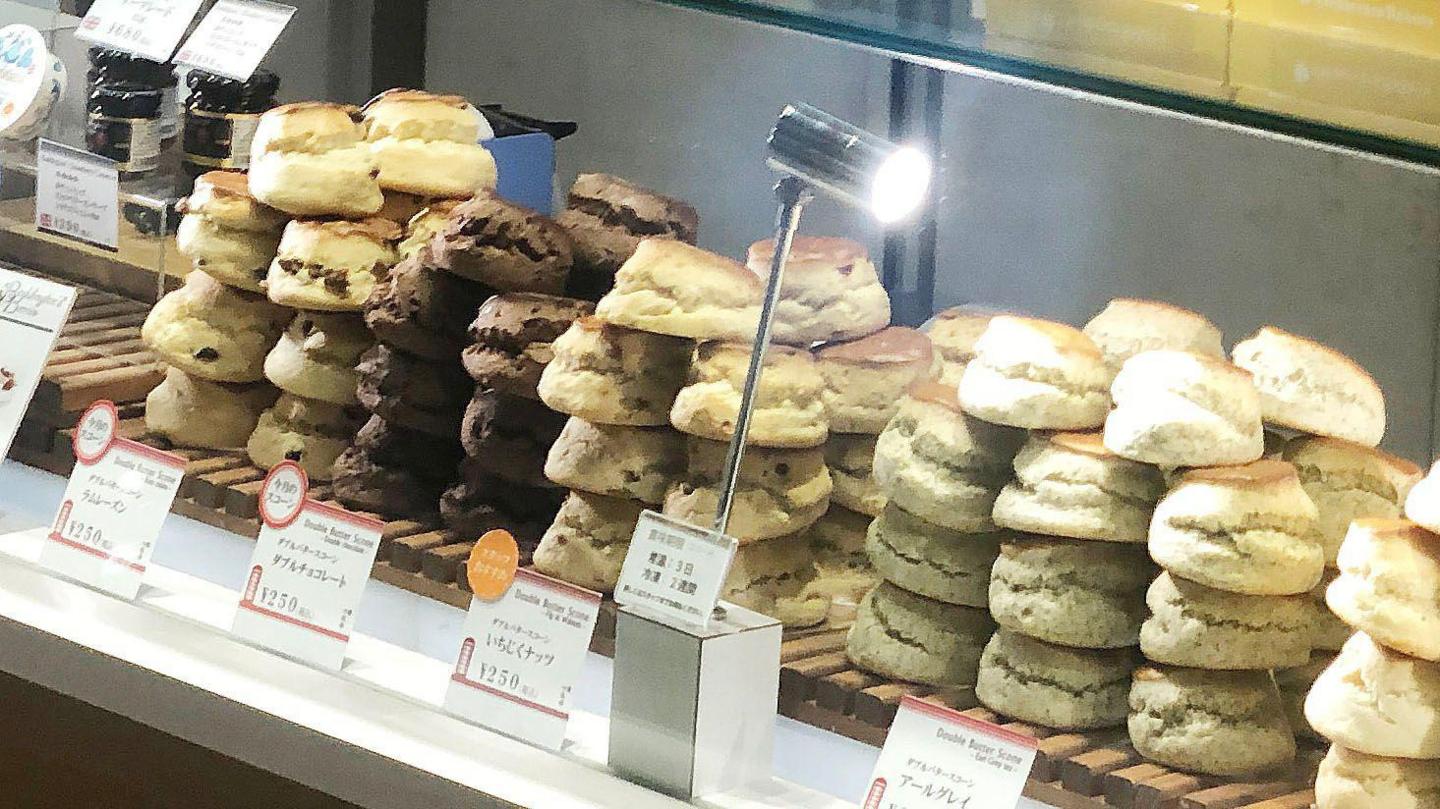 lots of scones stacked up with prices and descriptions in Japanese