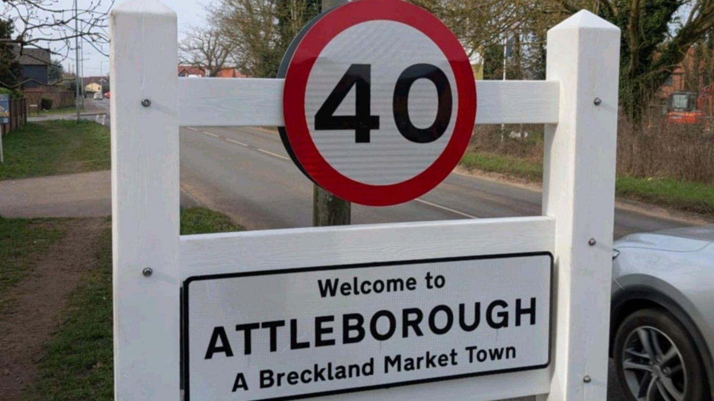 Road sign in black and white with a 40mph speed limit signage and the words saying: "Welcome to Attleborough A Breckland Market Town."