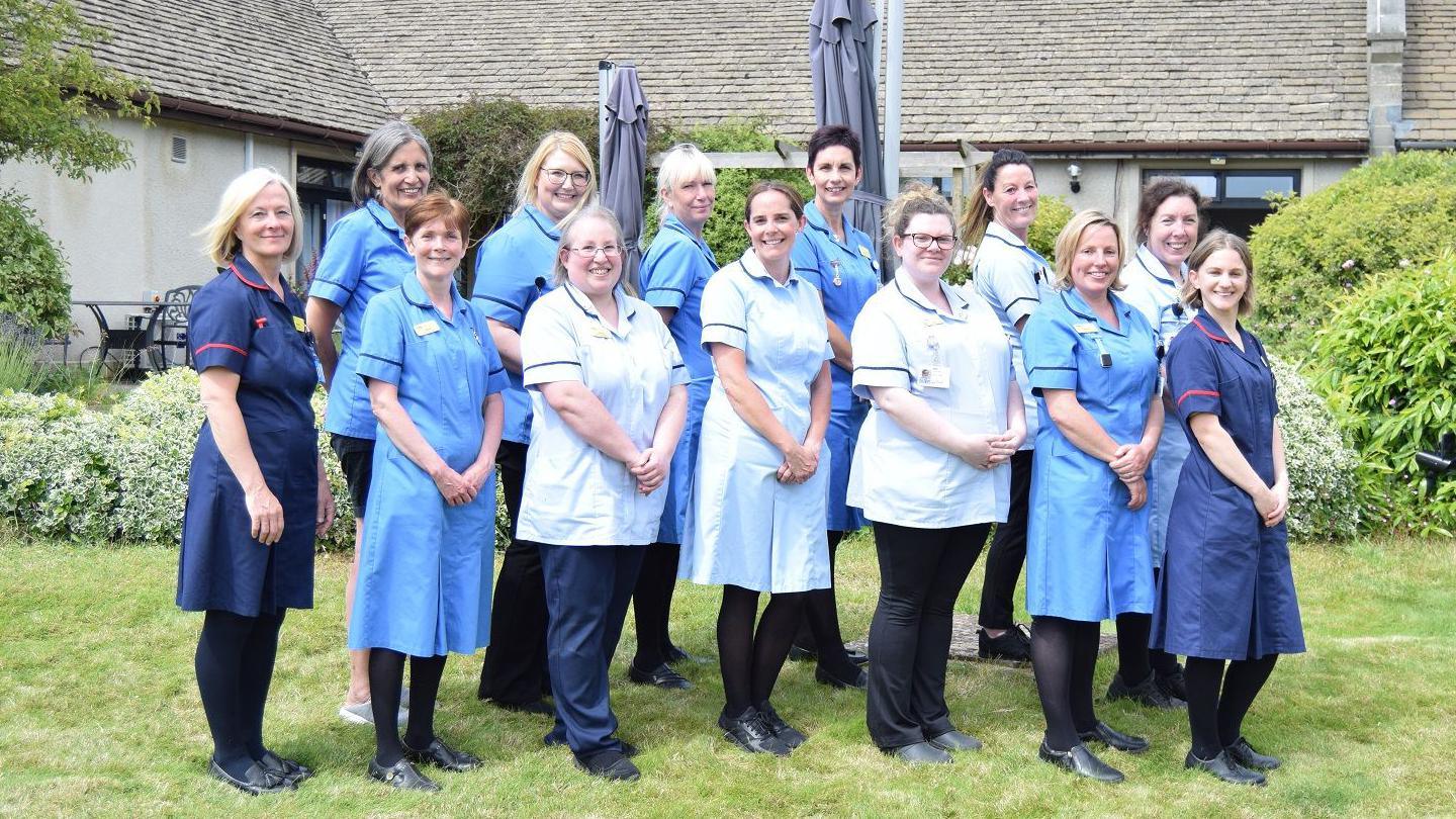 Staff members at Dorothy House Hospice Care pose for the camera in the grounds of the charity's Winsley headquarters.