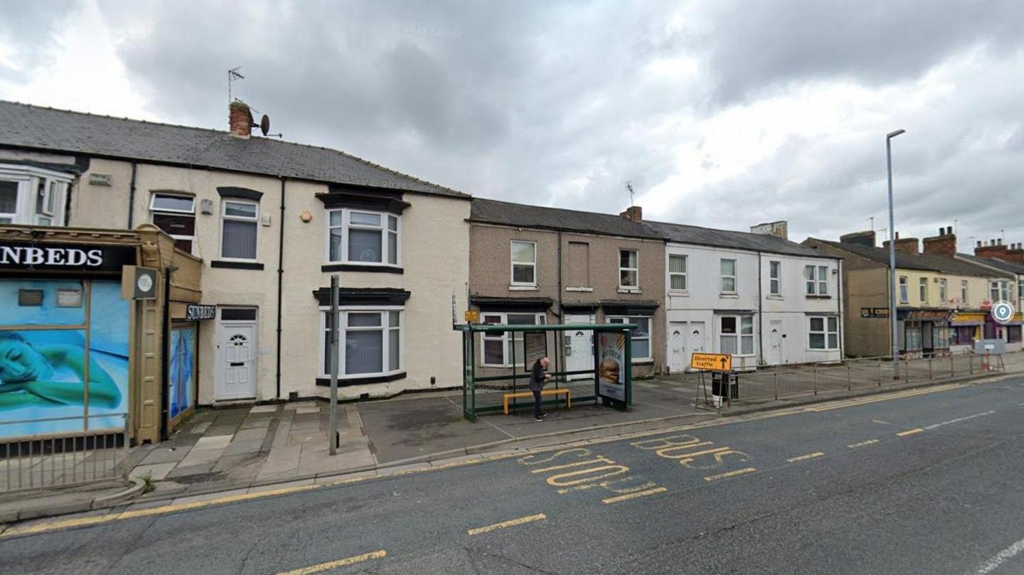 View of North Road and a bus stop and some houses behind