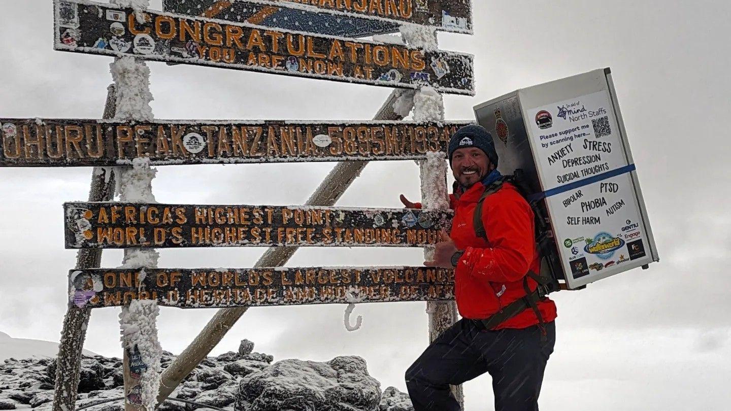 Michael Copeland carrying a fridge at the summit of Mount Kilimanjaro