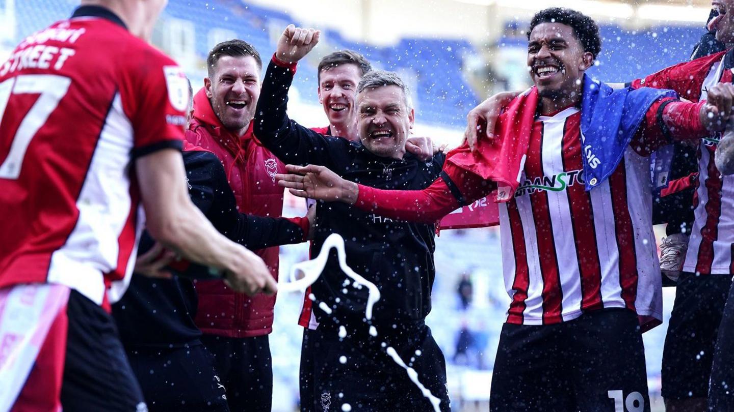 Michael Skubala celebrates with his Lincoln players as champagne is poured over the squad
