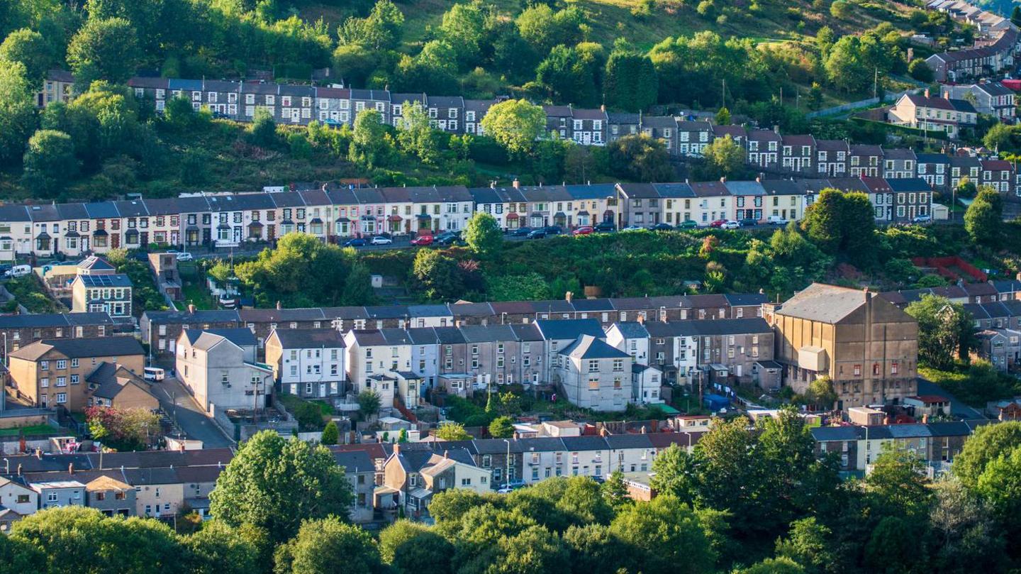 Rows of terraced houses in Wales with chimneys and slate roofs, in low sunshine