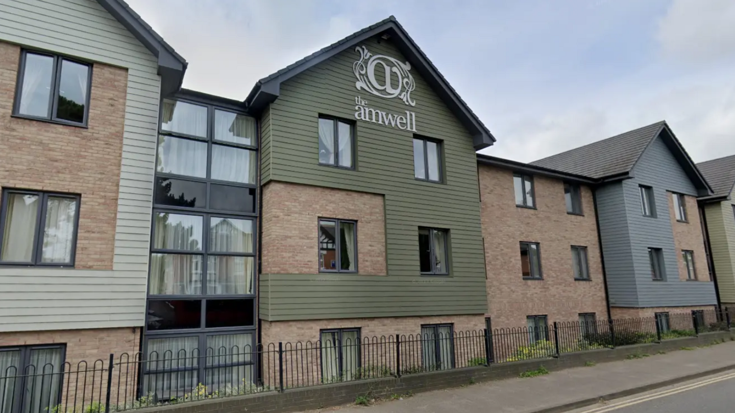 A light brick building with pastel green and blue cladding and glass frontage