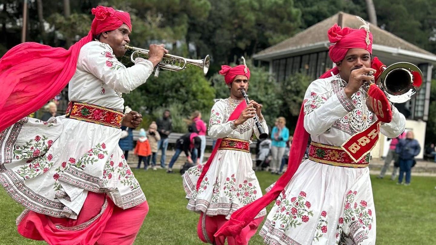 A group of men in traditional dress performing with trumpets