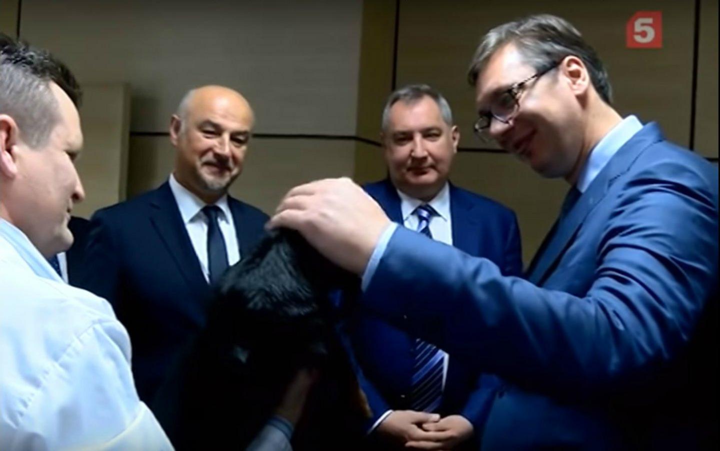 Serbian President Aleksandar Vucic strokes the dog after the experiment while Russian deputy PM Dmitry Rogozin (right) looks on