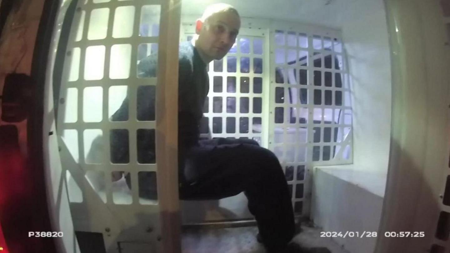 Antony Snook sat in the back of a police van after being arrested. The picture is from body worn footage of the arrest issued by Avon and Somerset Police.