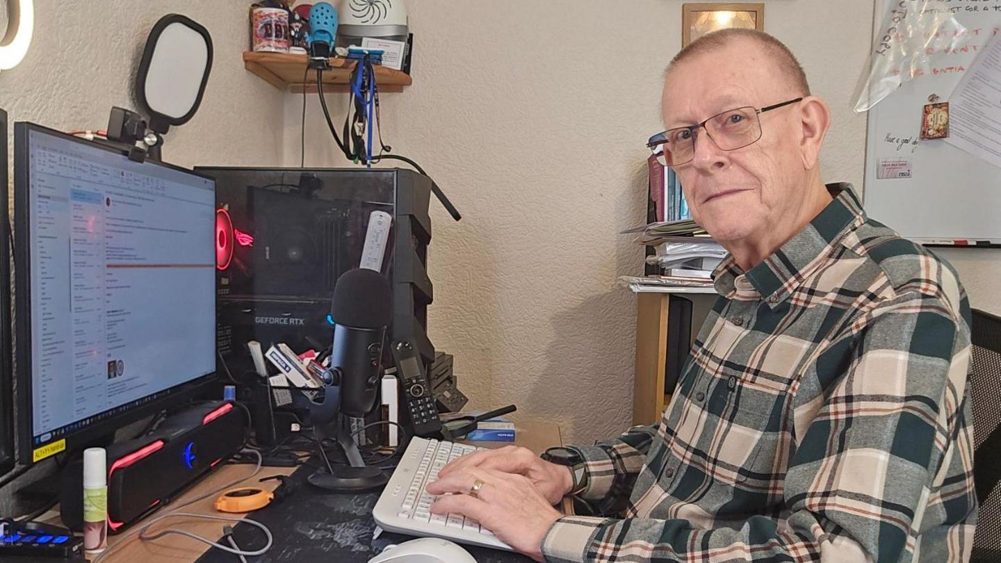 Pete Middleton sitting at his computer wearing a checked shirt