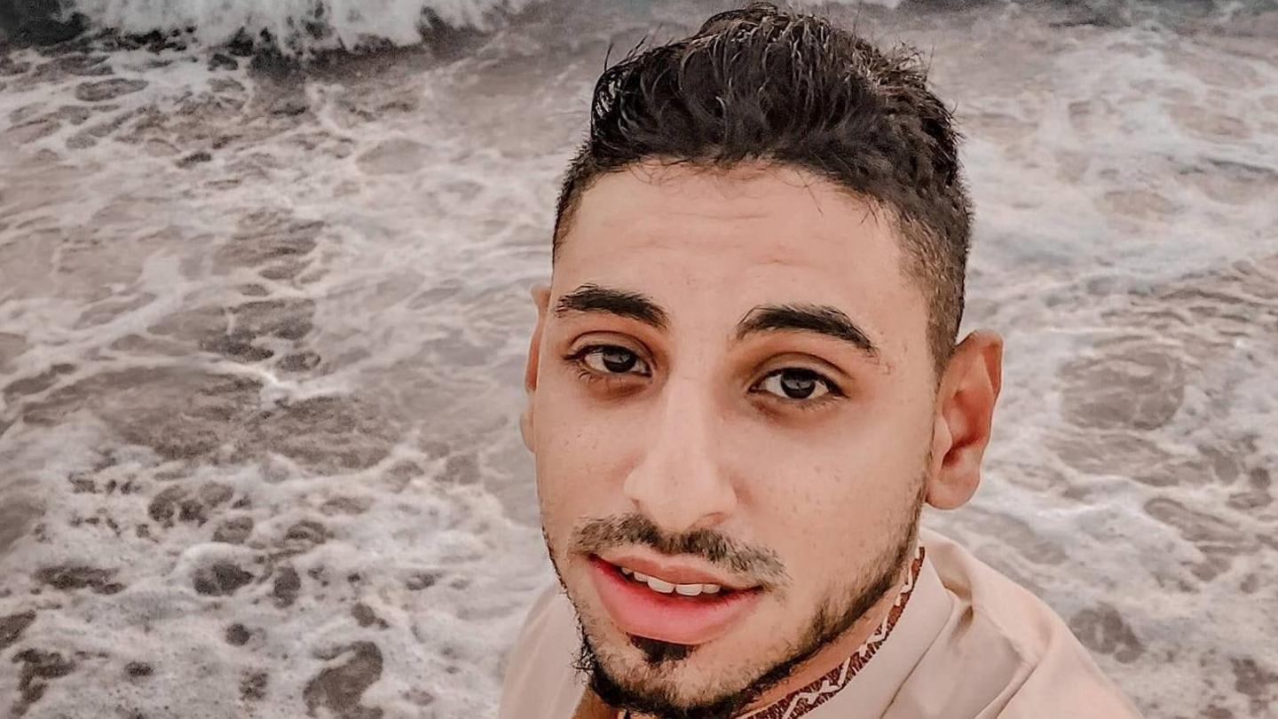 A young man, Mohamed Kullab, stares at the camera with the sea swirling under his feet