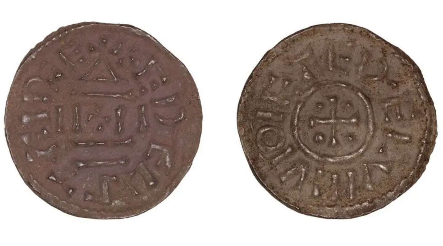 The front and back of a brown coin side by side. The first has what appear to be ancient runes on, the second as a plus sign in a circle and what looks like ancient runes around it. 