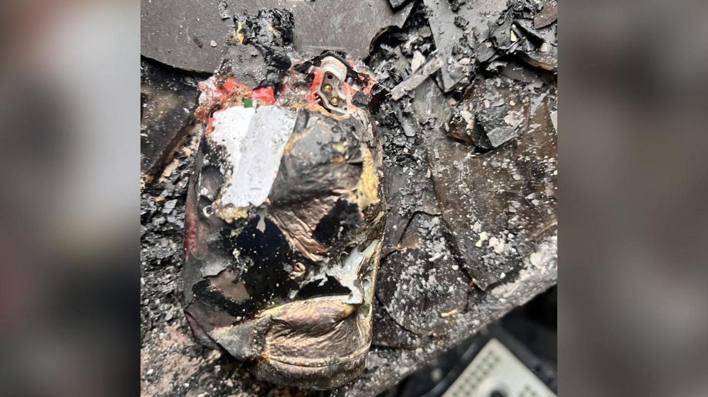 A close-up picture of a vape that has been destroyed in a fire, showing severe discoloration and extensive charring across its surface.