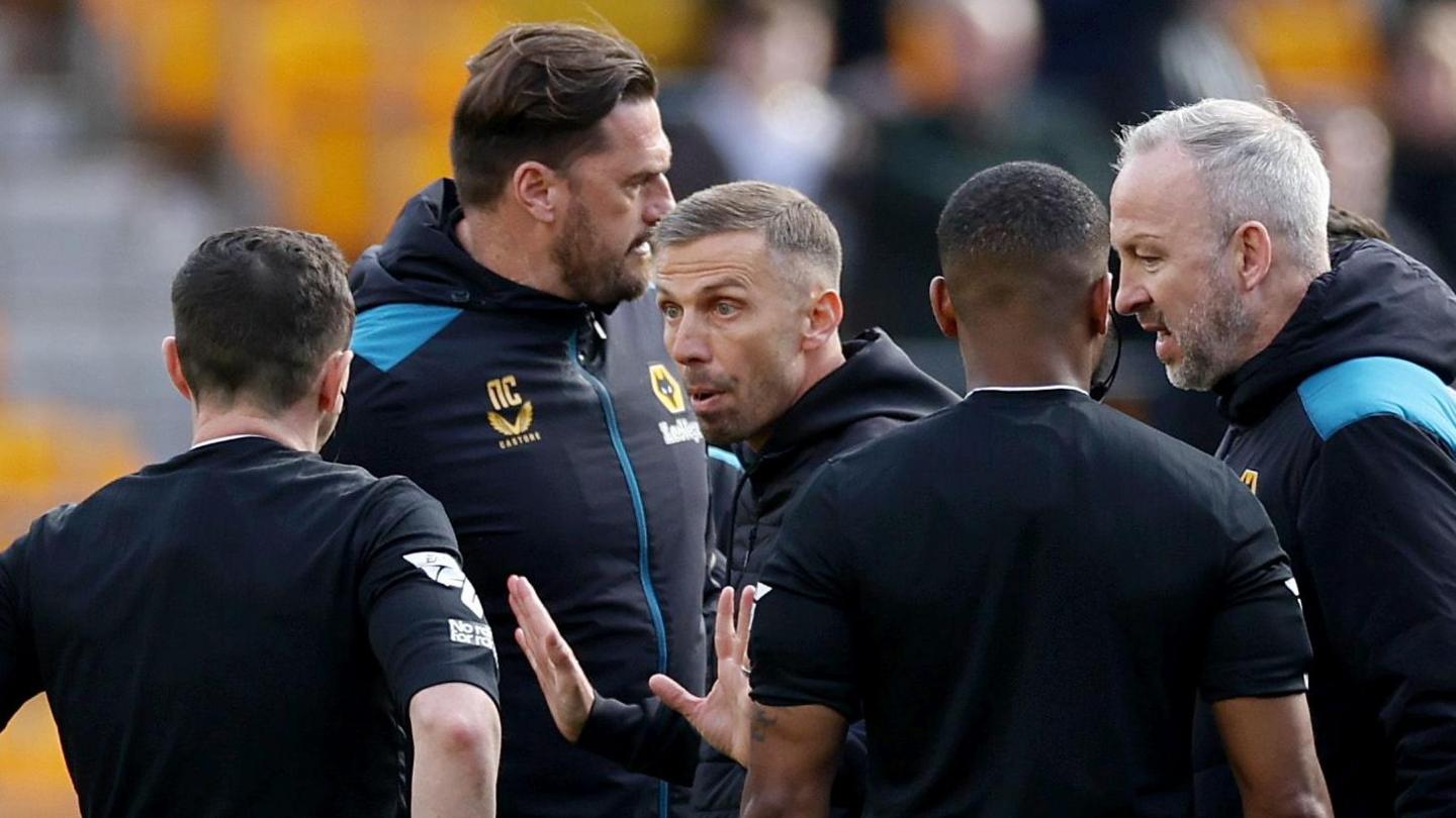 Gary O'Neil remonstrates with his arms out to referee Tony Harrington, who has his back to the camera, after Wolves' defeat to West Ham