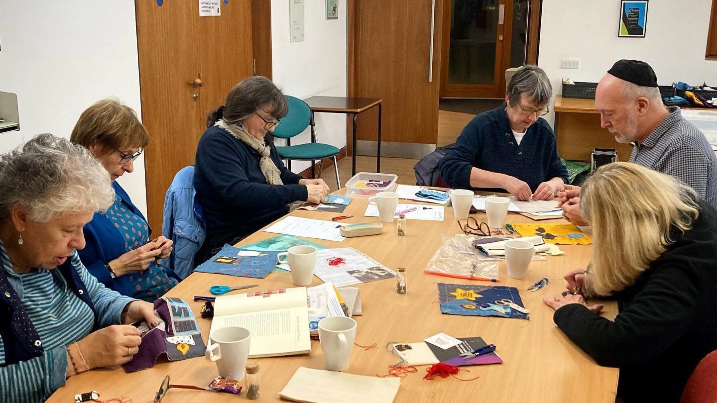 Six people around the table creating the squares for the quilt