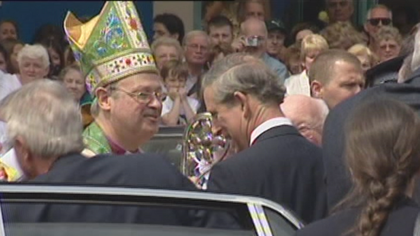 Former Bishop of Swansea and Brecon Anthony Pierce wearing his robes and a hat meets the then Prince Charles, wearing a suit and white shirt, in a crowded street in Swansea