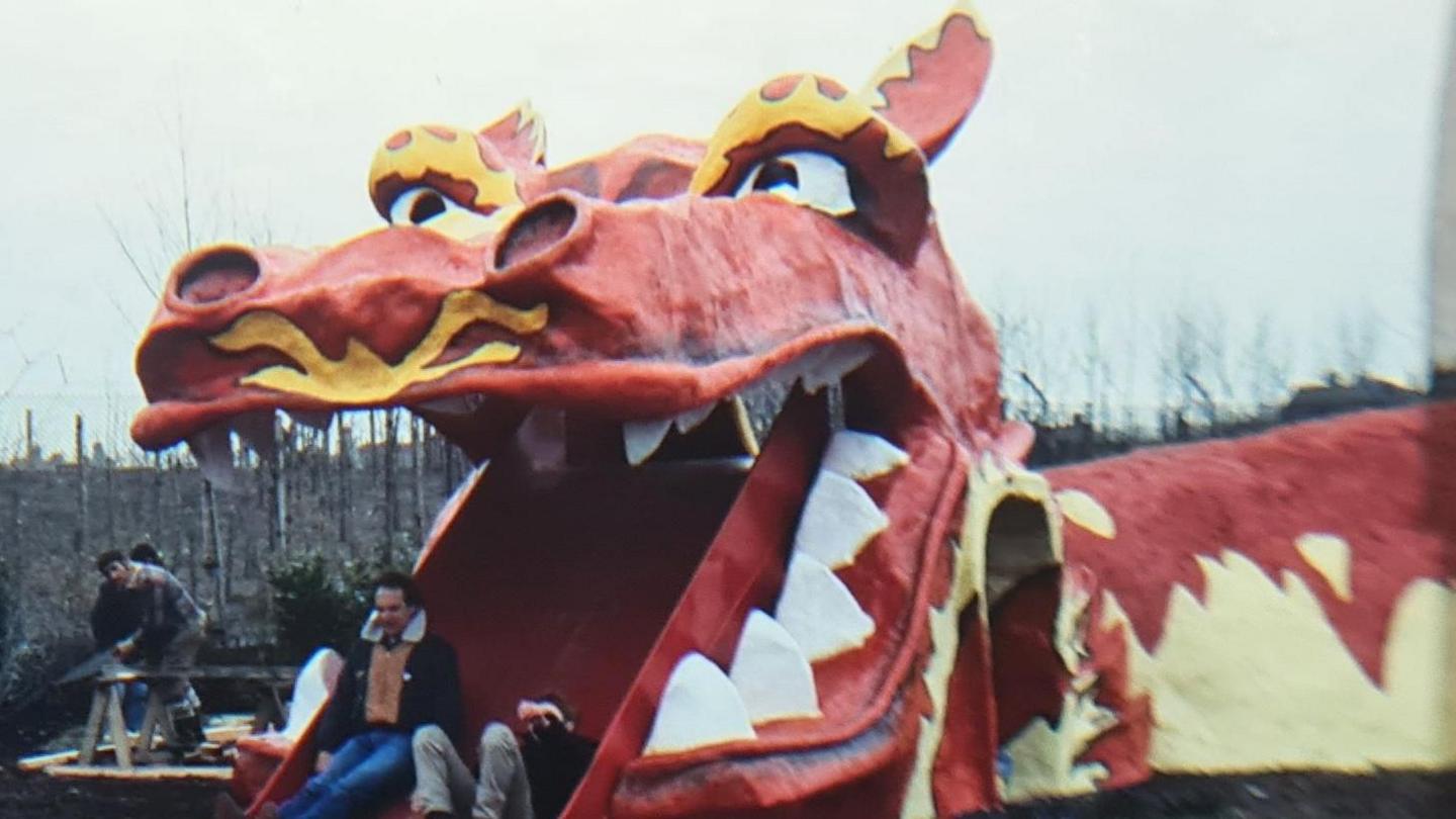 Theo Gay Anderson seen right on his back and Simon Groom finish the dragon slide. The dragon is a large red and yellow fibreglass construction. 