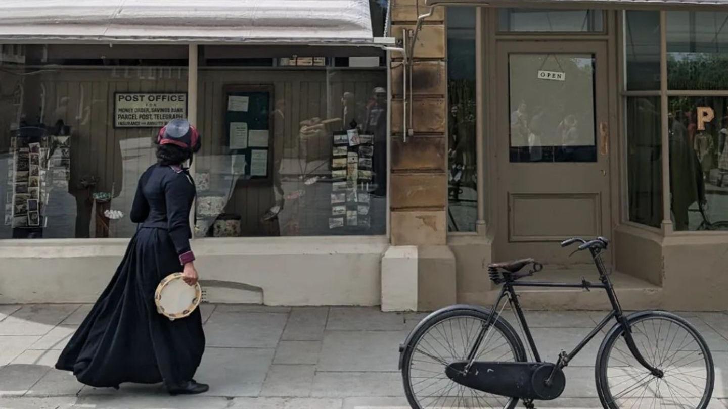 An actor in costume stands in front of Ramsden Post Office