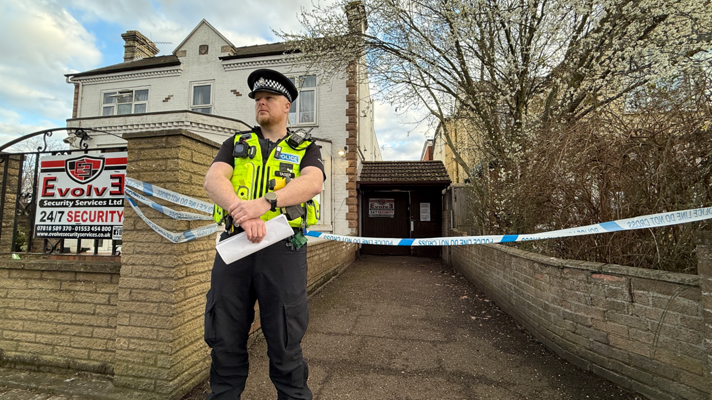 A police officer stands in front of a property in Chesterton Road, Cambridge. Blue and white police tape can be seen behind him.