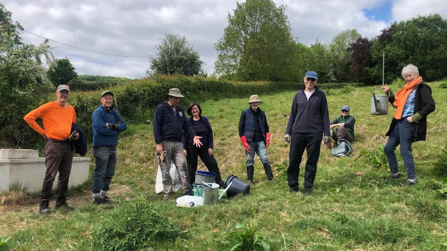 A group of people pose for the camera in a line as they stand in a field near Stroud in Gloucestershire