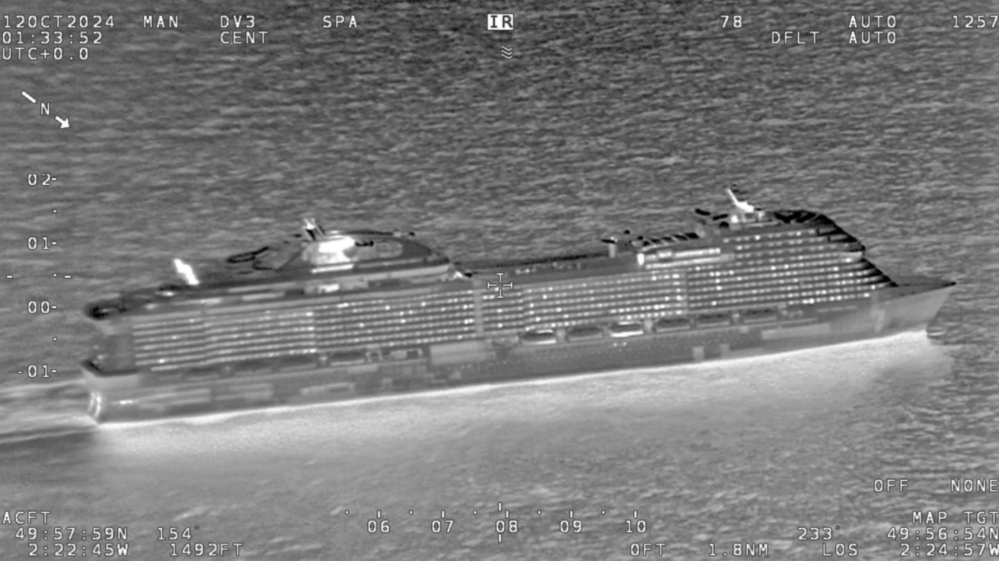 A thermal camera image of a large cruise ship on the sea. Light areas indicating heat show hundreds of windows, as well as hotspots where the water is churned up by the boat and its wake.