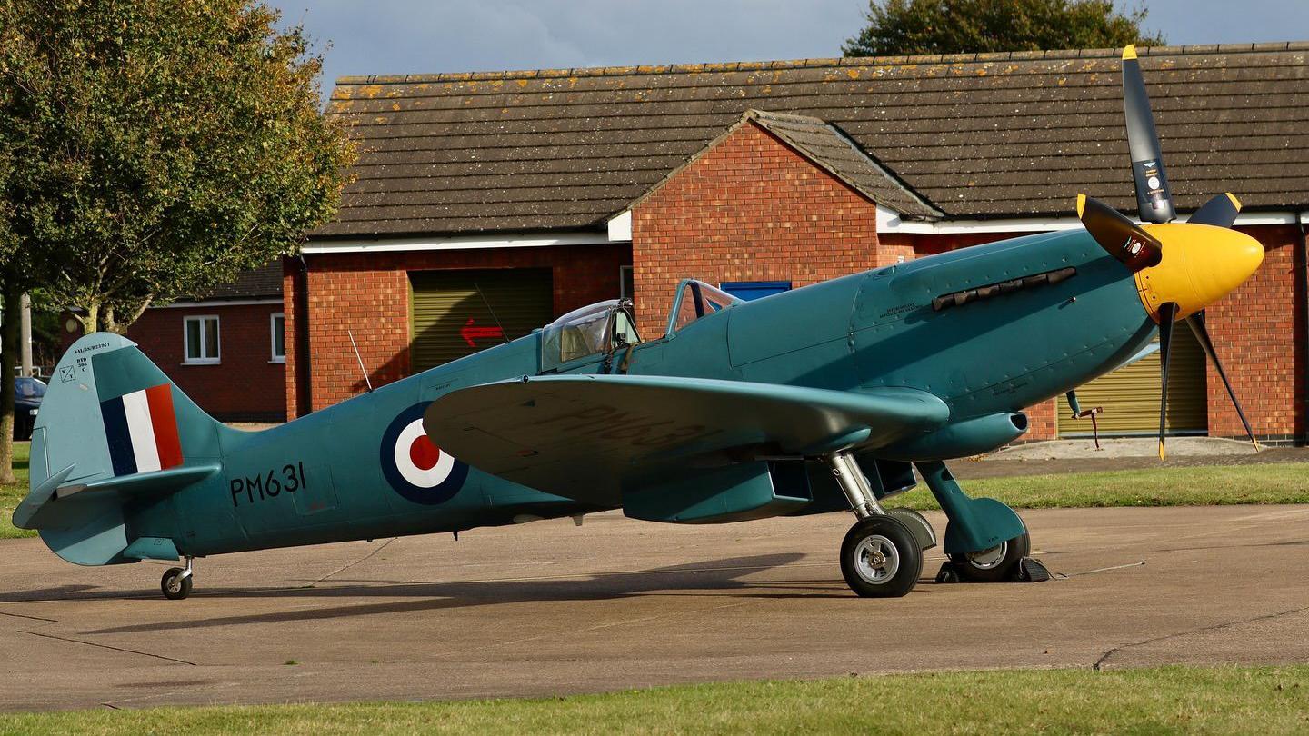 A green vintage spitfire with a yellow nose cone and RAF target symbol. It has the PM631 code on the side.